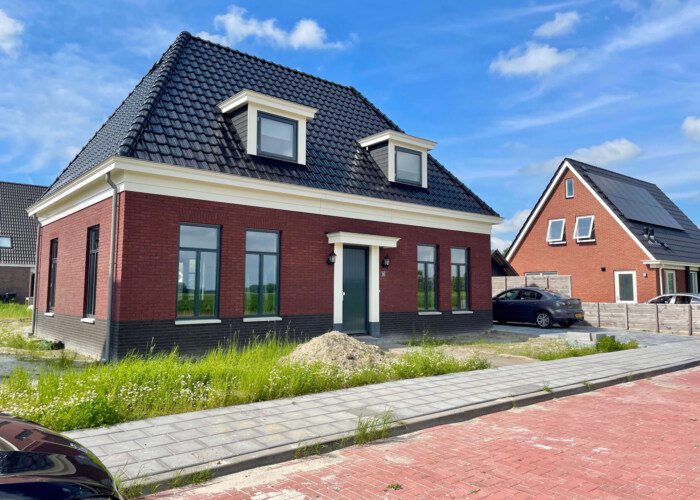 Woning met schildkap en blauwe dakpannen en rode baksteen